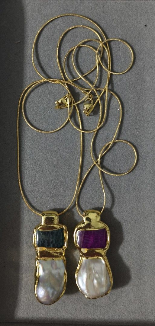 Necklaces with gemstone and pearl pendants (Category: Necklaces) located in Batangas. Submitted by decluttering_bliss (Listing ID 1465493113, Image 1). Description: - Set of 2 statement necklaces - Gold-plated snake chains with secure lobster clasps - Features colorful stones (dark textured with purple undertone and vibrant purple) - Accented with unique irregular pearl drops - Long length design that sits low on the chest.