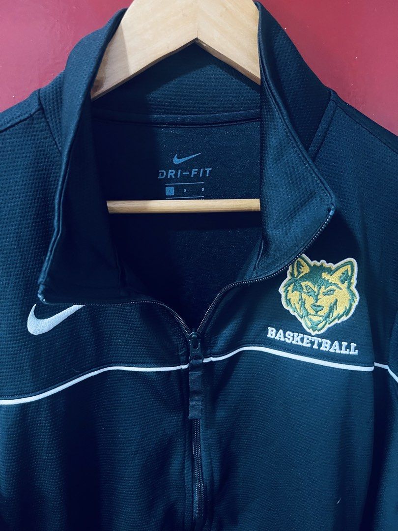 Nike black basketball warm-up jacket (Category: Activewear) located in Quezon City. Submitted by wacpon_061972 (Listing ID 1465434561, Image 2). Description: A black Nike Dri-FIT full-zip track jacket with a white swoosh logo and a green and yellow wolf team crest on the chest. (W-24/L-29).