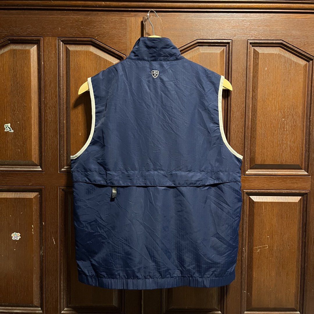 Nike Golf Navy Blue Zip-Up Vest (Category: Vests) located in Manila. Submitted by thriftyyyyy. (Listing ID 1465533485, Image 3). Description: - Brand: Nike Golf - Color: Navy blue with white piping trim - Material: Lightweight fabric with grid texture - Design: Full zip front, high collar, two zippered hand pockets - Details: Embroidered Nike swoosh on chest and Nike Golf logo patch on back collar - Condition: Excellent/Ready to wear.