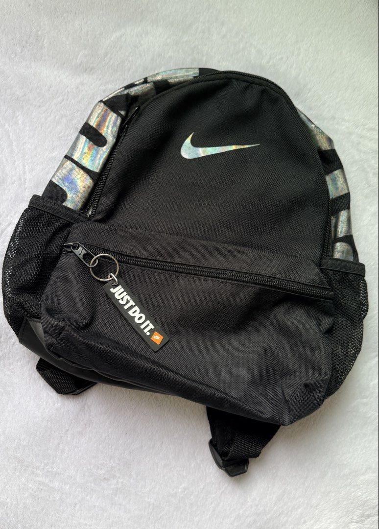 Nike Holographic Mini Backpack (Category: Backpacks) located in Quezon City. Submitted by shane_blueraee (Listing ID 1465402167, Image 1). Description: Nike mini backpack Color: Black with holographic top handle Pockets: Front zipped pocket with 'Just Do It' zipper tag, dual mesh side pockets Straps: Adjustable black shoulder straps - Condition: Pre-loved, faded holographic design (see pic) SF c/o buyer - delivery thru lalamove Meet up - SM North