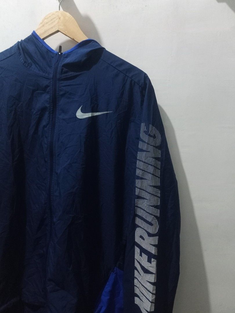 Nike Running Hooded Jacket Blue Size L (Category: Coats, Jackets and Outerwear) located in Taguig. Submitted by mvdsh0p2022 (Listing ID 1465511845, Image 2). Description: - Brand: Nike - Item: Running Jacket - Color: Dark blue with bright blue accents - Size: L (Tag on inner collar and wash label) - Features: Hooded, full-zip design, Nike Running text on left sleeve, large Nike logo graphic on the back - Material: 100% polyester Nike Running Jack