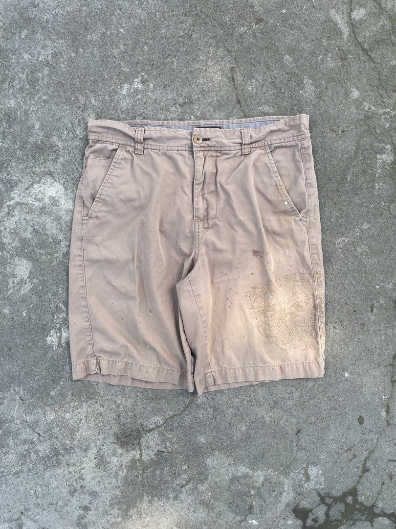 No Boundaries Khaki Shorts with Graphic Print (Category: Shorts) located in Manila. Submitted by chocoballsss (Listing ID 1465464671, Image 1). Description: - Brand: No Boundaries - Size: Regular fit - Color: Tan khaki - Details: Eye graphic print on lower left leg, front pockets, belt loops, button closure - Material: Lightweight cotton - Condition: Shows minor paint splatters and staining from use.