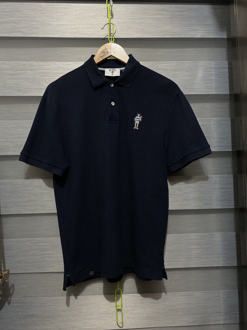 OLIVER Navy Polo Shirt with Character Patch (Category: Tshirts & Polo Shirts ) located in Butuan. Submitted by nielben13 (Listing ID 1465498925, Image 1). Description: - Brand: OLIVER - Color: Navy Blue - Size: 100 - Style: Short sleeves, button collar, and side slits at the hem - Detail: Embroidered character patch on the left chest - Condition: Clean, well-maintained, with minimal signs of wear.