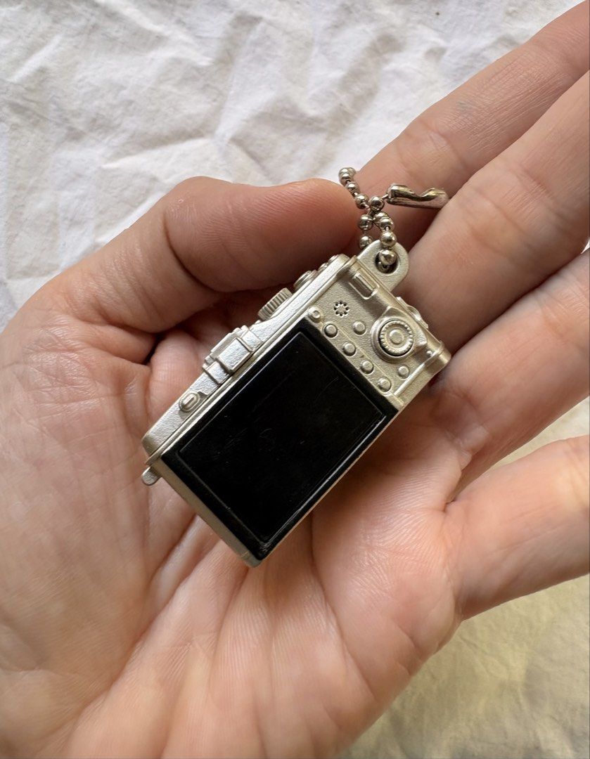 Olympus PEN Camera Miniature Keychain (Category: Cameras) located in Tuguegarao City. Submitted by jasminecoll (Listing ID 1465541185, Image 3). Description: - Color: Silver and black - Design: Detailed miniature Olympus camera replica with textured grip and protruding lens barrel - Features: Realistic top dial buttons and attached ball chain - Use: Pocket-sized novelty accessory, perfect for camera fans or daily bag decoration Location Tuguegara