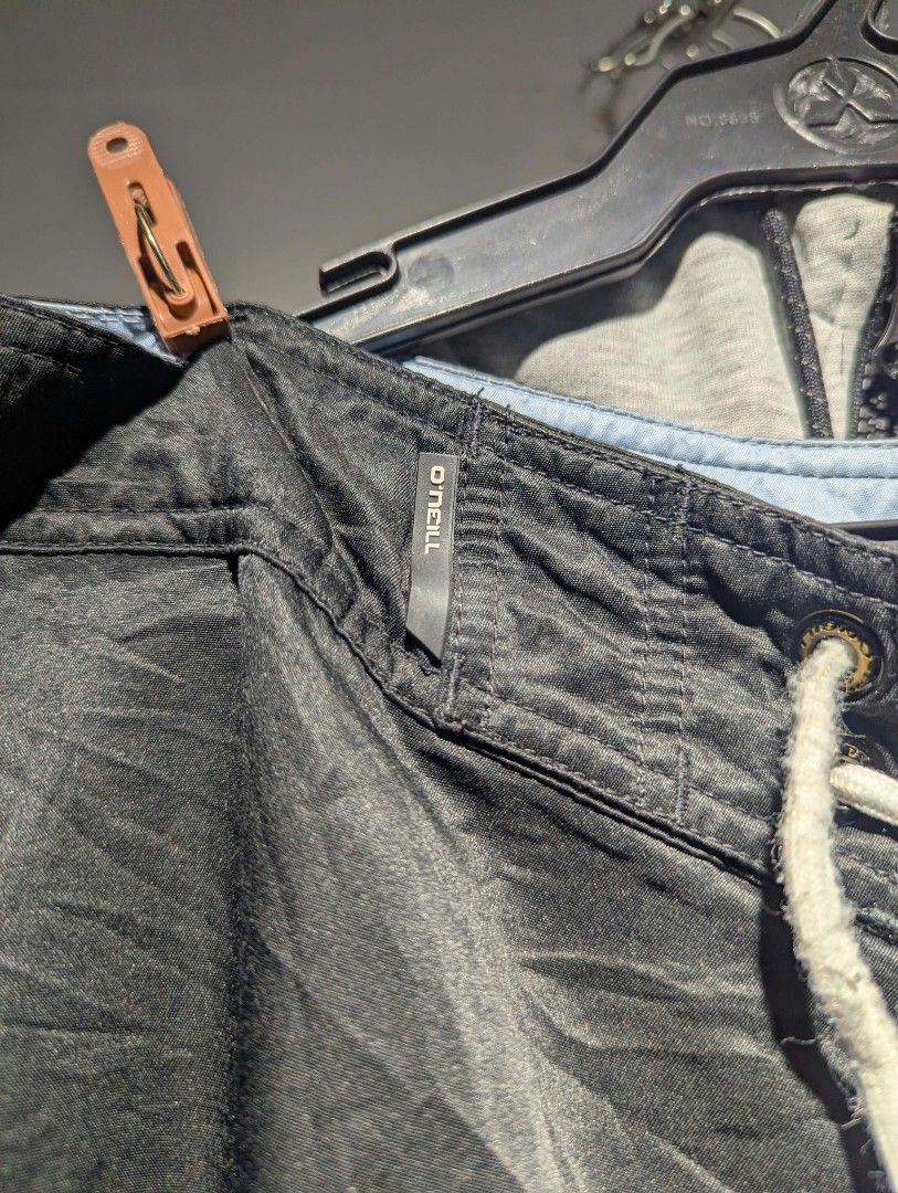 O'Neill Black Cargo Board Shorts with Drawstring (Category: Shorts) located in Manila. Submitted by grandwater.53a8ce (Listing ID 1465492651, Image 3). Description: - Brand: O'Neill - Color: Black with blue contrast piping - Waist: White adjustable drawstring with metal grommets - Pockets: Dual side cargo pockets (one features embroidered logo and wave graphic) - Details: O'Neill wave logo print near the back waistband; fabric has a slight sheen 