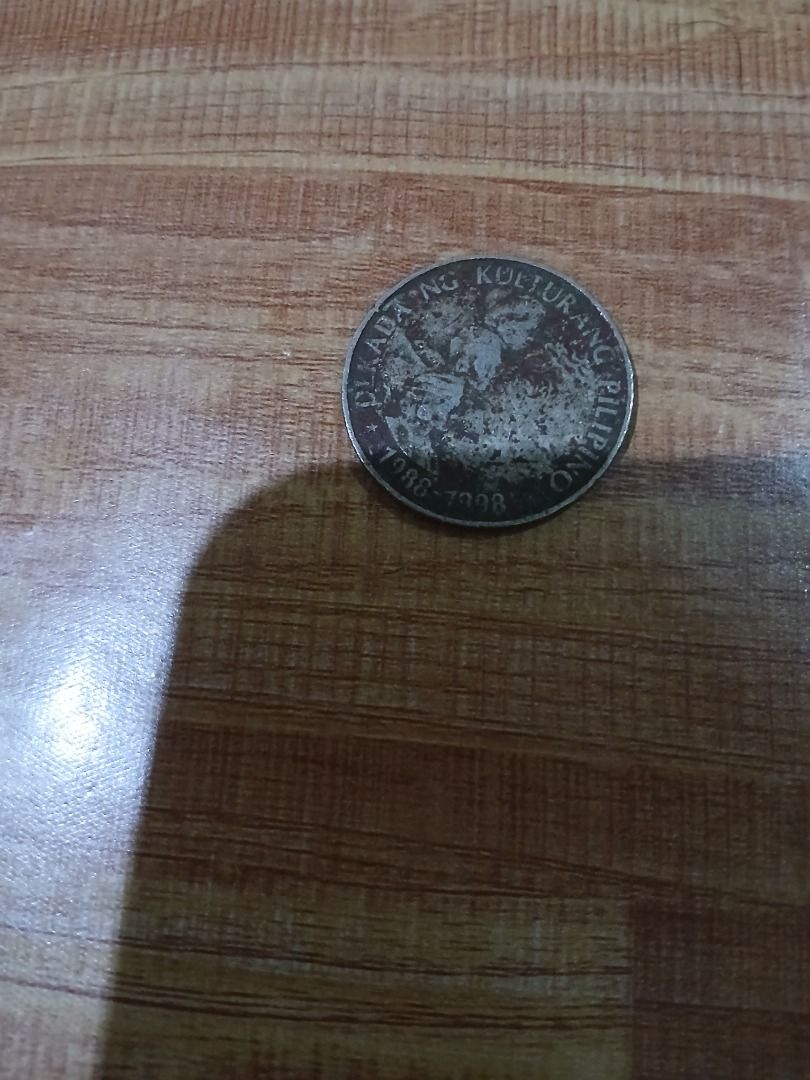 Philippine 1 Piso Coin 1989 (Category: Currency) located in Caloocan City. Submitted by vastdolphin.79423c (Listing ID 1465476680, Image 2). Description: - Item: 1989 Philippine 1 Piso Coin - Commemorative: Dekada ng Kulturang Pilipino (1988-1998) - Obverse: Republica ng Pilipinas design - Condition: Heavily circulated with visible wear, tarnish, and scratches - Details: Lettering and raised designs remain clear and legible.