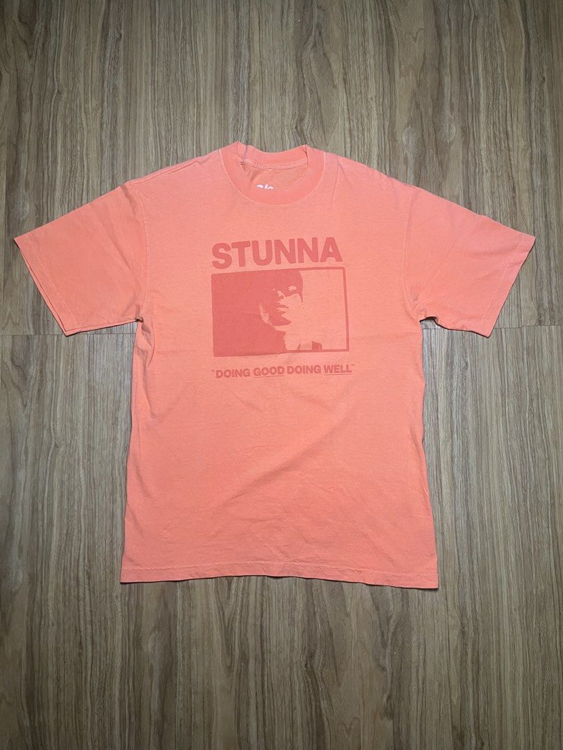 P-Lo Stunna Medium •20.5x29.5 (Category: Shirts) located in Cebu City. Submitted by guttathreads (Listing ID 1465429784, Image 1). Description: - Brand: P-Lo - Color: Peach - Size: Medium - Material: 100% cotton, Made in USA - Design: Front portrait graphic with 'STUNNA' and 'DOING GOOD DOING WELL' text - Style: Short sleeves, crew neck - Condition: Light fading around the collar.