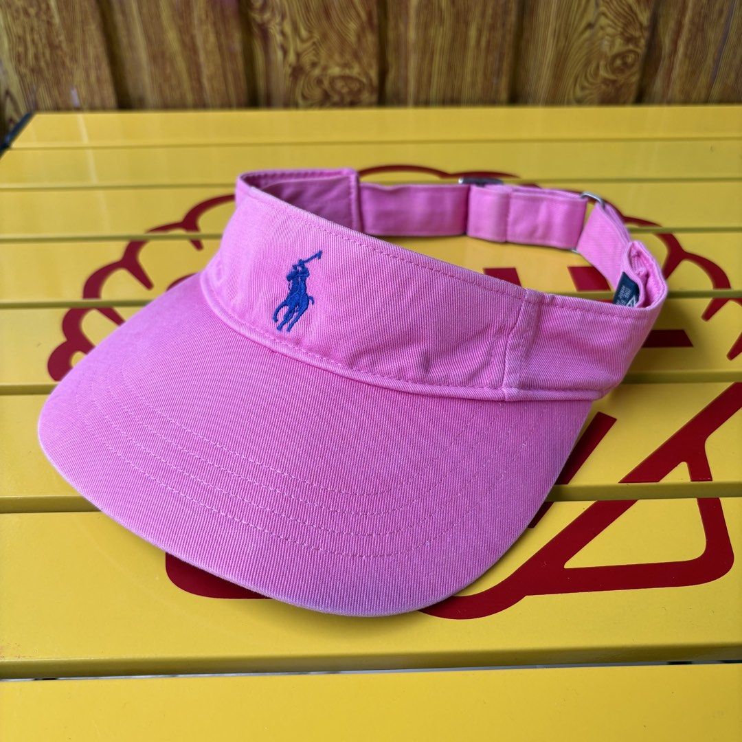 Polo Ralph Lauren Pink Sun Visor (Category: Hats & Beanies) located in Dapitan. Submitted by payt3es_thrift. (Listing ID 1465392322, Image 1). Description: - Brand: Polo Ralph Lauren - Color: Bright pink with classic blue embroidered pony - Fit: Adjustable metal strap in the back, one size fits most - Details: Navy interior label, made in China - Condition: Great shade for sunny days out!.
