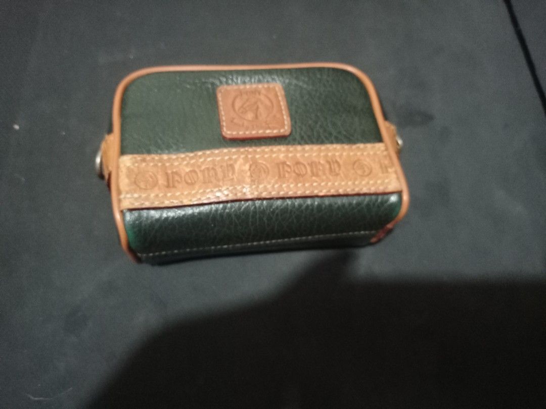 Pony Brand Leather Pouch Green Tan (Category: Luxury Bags & Wallets) located in Manila. Submitted by luckyeagle-7ff8 (Listing ID 1465478375, Image 1). Description: - Color & Material: Green textured leather with chic tan trim accents - Design: Features embossed pony text and a classic stamped logo patch - Versatile Carry: Includes sturdy belt loops on the back for waist or belt bag styling - Closure: Smooth zipper closure running along the top an