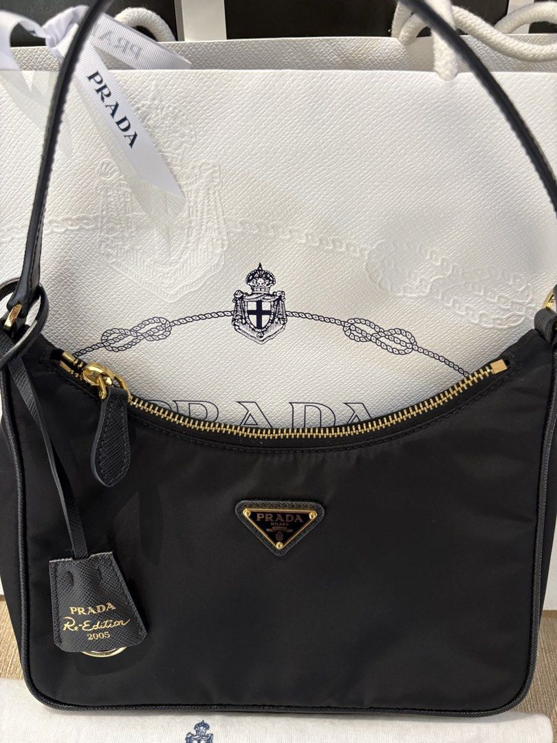 Prada Re-Edition 2005 Black Nylon Shoulder Bag (Category: Luxury Bags & Wallets) located in Pasig City. Submitted by mysticgem.b88cb8 (Listing ID 1465401382, Image 3). Description: - Authentic Prada Re-Edition 2005 shoulder bag in classic black nylon - Features elegant gold-tone hardware and secure zip closure - Includes matching Saffiano leather keychain tag with gold lettering - Comes with original dust bag, store paper bag, and authenticity ca