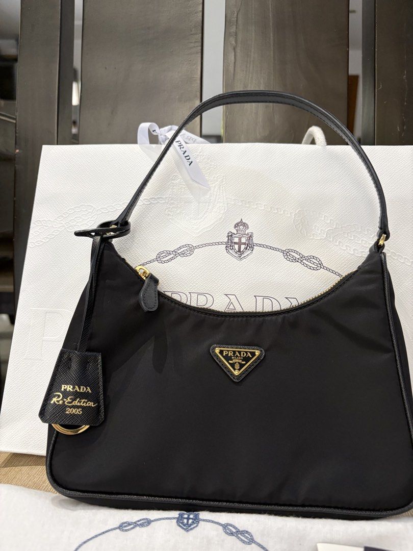 Prada Re-Edition 2005 Black Nylon Shoulder Bag (Category: Luxury Bags & Wallets) located in Pasig City. Submitted by mysticgem.b88cb8 (Listing ID 1465401382, Image 2). Description: - Authentic Prada Re-Edition 2005 shoulder bag in classic black nylon - Features elegant gold-tone hardware and secure zip closure - Includes matching Saffiano leather keychain tag with gold lettering - Comes with original dust bag, store paper bag, and authenticity ca