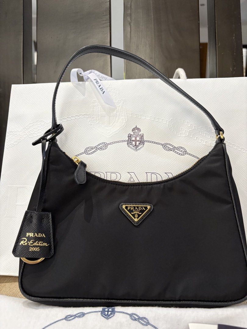 Prada Re-Edition 2005 Black Nylon Shoulder Bag (Category: Luxury Bags & Wallets) located in Pasig City. Submitted by mysticgem.b88cb8 (Listing ID 1465401382, Image 1). Description: - Authentic Prada Re-Edition 2005 shoulder bag in classic black nylon - Features elegant gold-tone hardware and secure zip closure - Includes matching Saffiano leather keychain tag with gold lettering - Comes with original dust bag, store paper bag, and authenticity ca