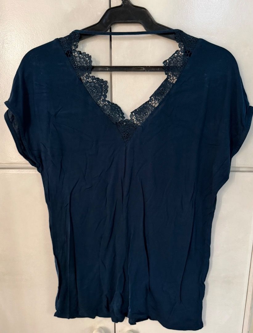 Dark Blue Blouse / Top from Promod (Category: Blouses) located in Santa Rosa. Submitted by biancamarie0404 (Listing ID 1465436242, Image 3). Description: - Brand: Promod - Color: Dark blue - Neckline: V-neck with metallic gold trim - Back Details: Deep V-shape with dark lace panels and a horizontal top strap - Fit: Relaxed and soft - Style: Versatile for casual or dressed-up outfits.