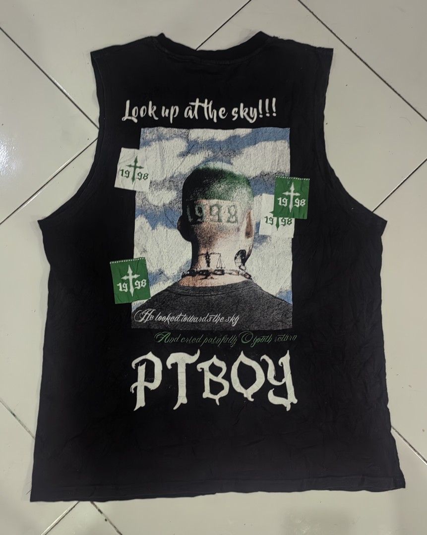 PTBOY Graphic Print Black Tank Top (Category: Tshirts & Polo Shirts ) located in Manila. Submitted by livedolphin_68dee2 (Listing ID 1465485904, Image 1). Description: - Brand: PTBOY - Style: Black sleeveless tank top with a bold streetwear/vintage aesthetic - Design Front: "PAINFULLY" arched over a gothic cross graphic - Design Back: Large graphic print of a figure with "1998", clouds, and green crosses - Fabric: Heavy distressed acid wash textu
