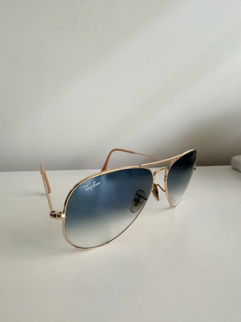 Ray-Ban Aviator Sunglasses Gold Blue Gradient (Category: Sunglasses & Eyewear) located in Paranaque City. Submitted by inmycloset08 (Listing ID 1465413774, Image 3). Description: Style: Classic Aviator with double bridge design Frame: Gold-tone metal with beige temple tips Lenses: Blue gradient with iconic logo on the right lens ✅ slightly used, discolored nose pads and some discoloration on the frame due to long time storage but not too visible 