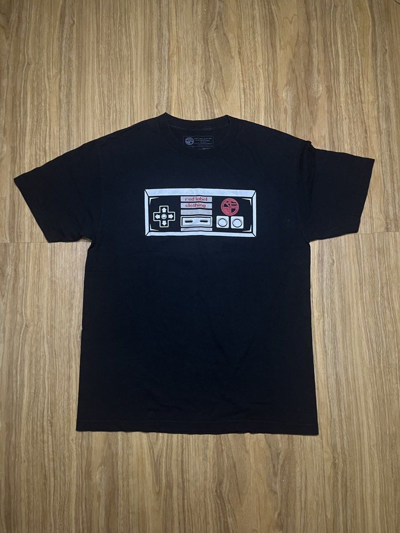 Red Label Clothing Large •21x29 (Category: Tshirts & Polo Shirts ) located in Cebu City. Submitted by guttathreads (Listing ID 1465429766, Image 1). Description: - Brand: Red Label Clothing - Color: Black - Style: Short sleeve crew neck t-shirt - Design: Retro NES controller graphic on chest; detailed crossed NES Zappers, consoles, and ornate scrollwork on the back - Condition: Excellent, no obvious flaws or fading - Size: Standard fit - Ideal fo