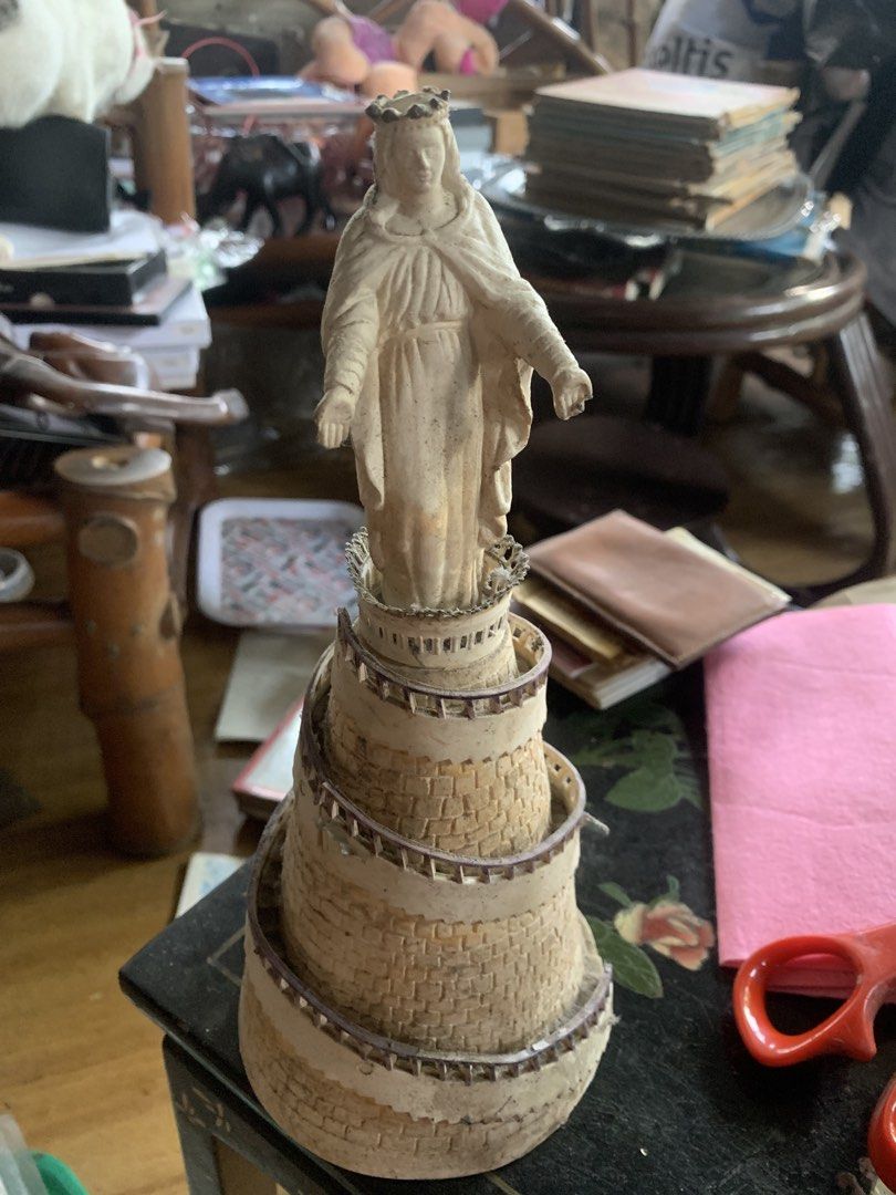 Religious Statue Figurine Mary Tower (Category: Religious Items) located in Quezon City. Submitted by sojisup (Listing ID 1465489825, Image 1). Description: - Elegant statue of Mary standing on a detailed spiral stone tower - Cream and beige color scheme with textured stonework and ramp railings - Features intricate details including a crown and flowing robes - Compact size, ideal for desk or shelf collections - Note: Minor dust and dirt in crevi