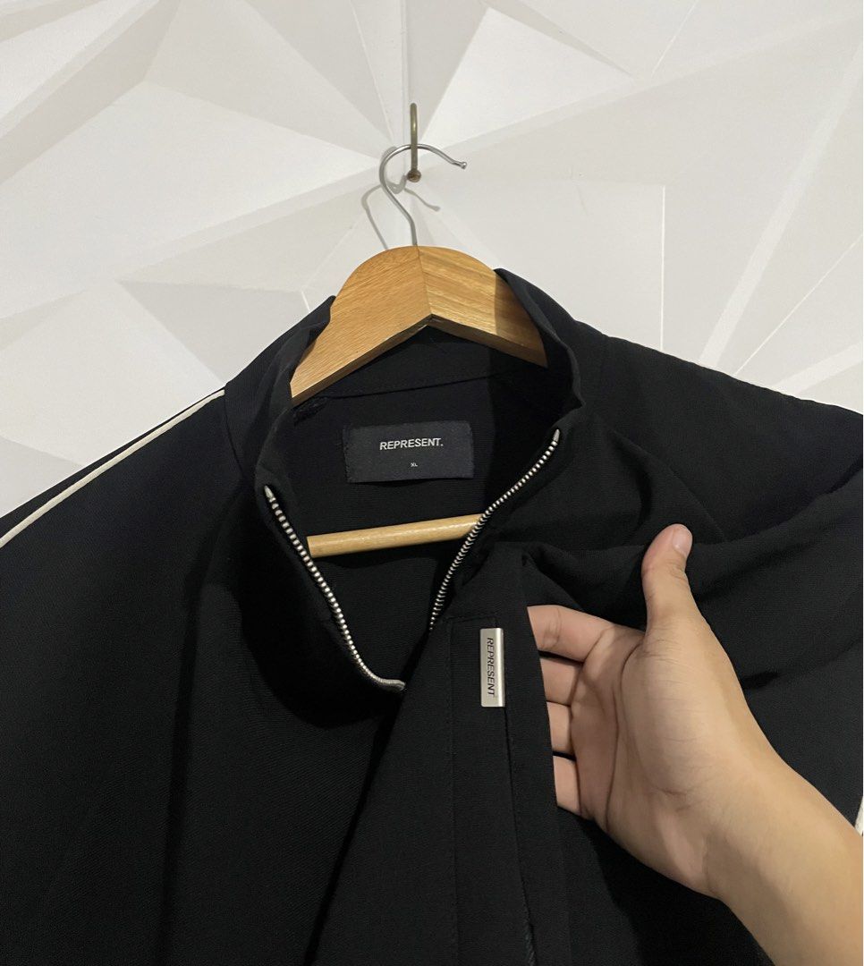 Represent Black Track Jacket with White Piping Size XL (Category: Coats, Jackets and Outerwear) located in Cabuyao City. Submitted by ParadisethriftedPh (Listing ID 1465463608, Image 3). Description: Cr: 9.8/10 Dimensions W: 24.5 L: 25 - Color: Classic black with white piping on sleeves - Size: XL on tag - Material: 100% premium cotton - Features: Full zip closure with custom 'R' hardware pulls, stand collar, ribbed cuffs and hem - Pockets: Conve