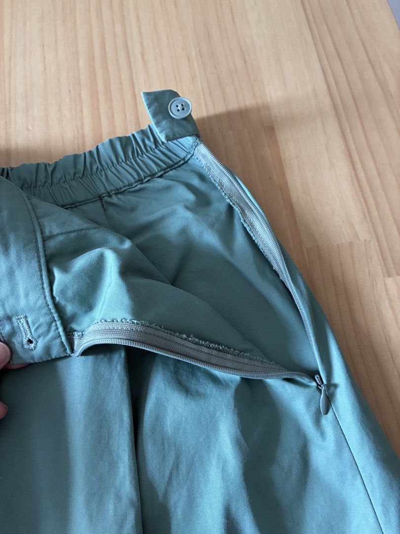 Muji Pleated Skirt (Category: Skirts) located in Dasmarinas. Submitted by fermosaclothing (Listing ID 1465414825, Image 3). Description: - Color: Sage green (solid) - Length: Midi (falls right below the knee) - Fit: High-waisted with partially elasticized back waistband - Closure: Side zipper with a single button - Features: Box pleats all around and deep pockets on both sides - Fabric: Lightweight and comfortable - Styling tip: Pairs well with b