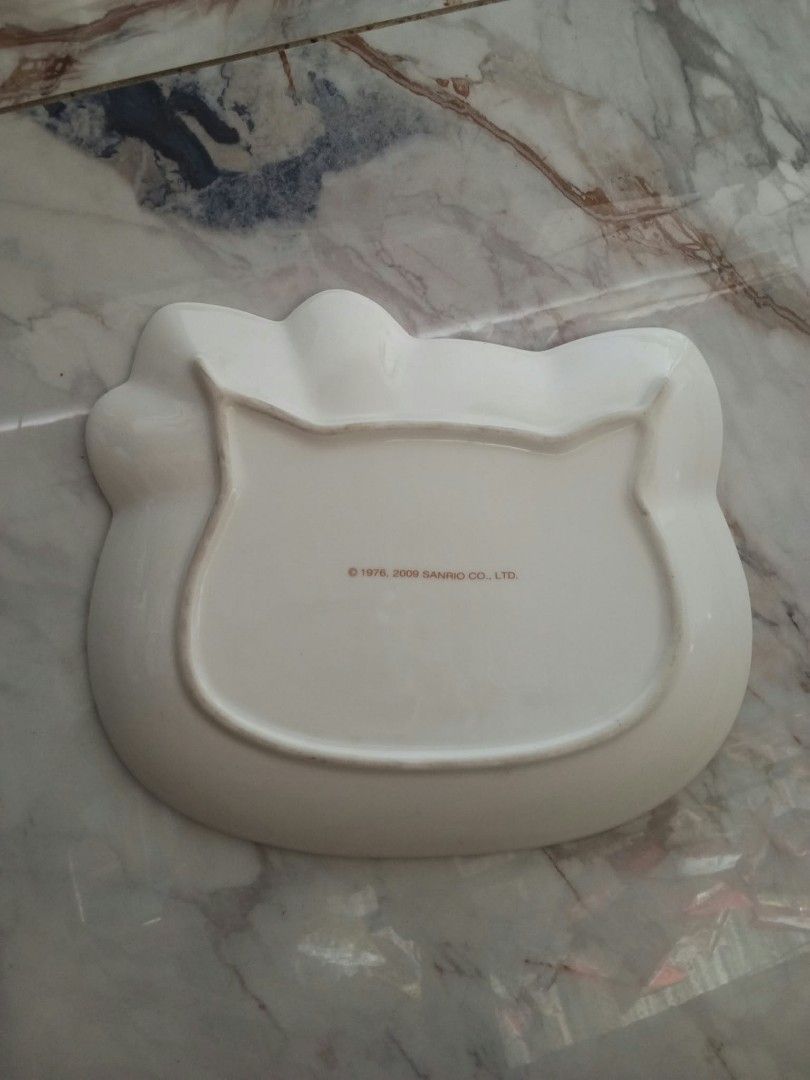 Sanrio Hello Kitty Face Ceramic Plate 1976 2009 (Category: Dinnerware & Cutlery) located in Davao. Submitted by mengsmixitems (Listing ID 1465423636, Image 2). Description: - Authentic Sanrio Kitty shaped ceramic plate - Features iconic white base, pink bow, and yellow nose - Official Sanrio stamp on bottom (dated 1976, 2009) - Raised edges, ideal for snacks or small dishes - Pristine condition: clean, zero chips, and no cracks - Must-have collec
