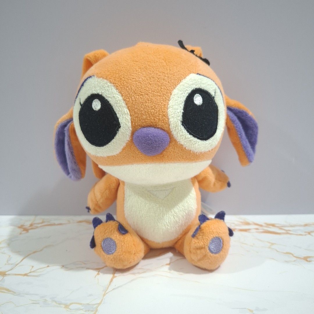 SEGA 2009 Orange Stitch Plush Toy (Category: Plushies & Soft Toys) located in Baguio. Submitted by marjshane11317 (Listing ID 1465528462, Image 1). Description: - Authentic SEGA 2009 Disney Stitch plush toy - Rare bright orange fur with purple ears, nose, and paw pads - Big black embroidered eyes with white highlights - Compact size: approximately 15 cm tall - Official tag still attached at the back - Super clean condition, ideal for collectors.