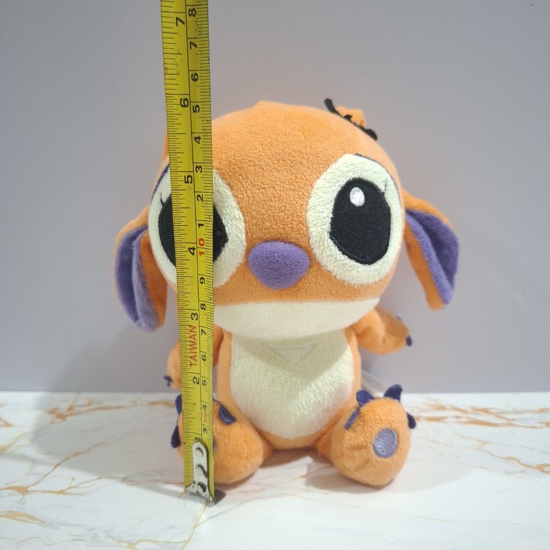 SEGA 2009 Orange Stitch Plush Toy (Category: Plushies & Soft Toys) located in Baguio. Submitted by marjshane11317 (Listing ID 1465528462, Image 2). Description: - Authentic SEGA 2009 Disney Stitch plush toy - Rare bright orange fur with purple ears, nose, and paw pads - Big black embroidered eyes with white highlights - Compact size: approximately 15 cm tall - Official tag still attached at the back - Super clean condition, ideal for collectors.