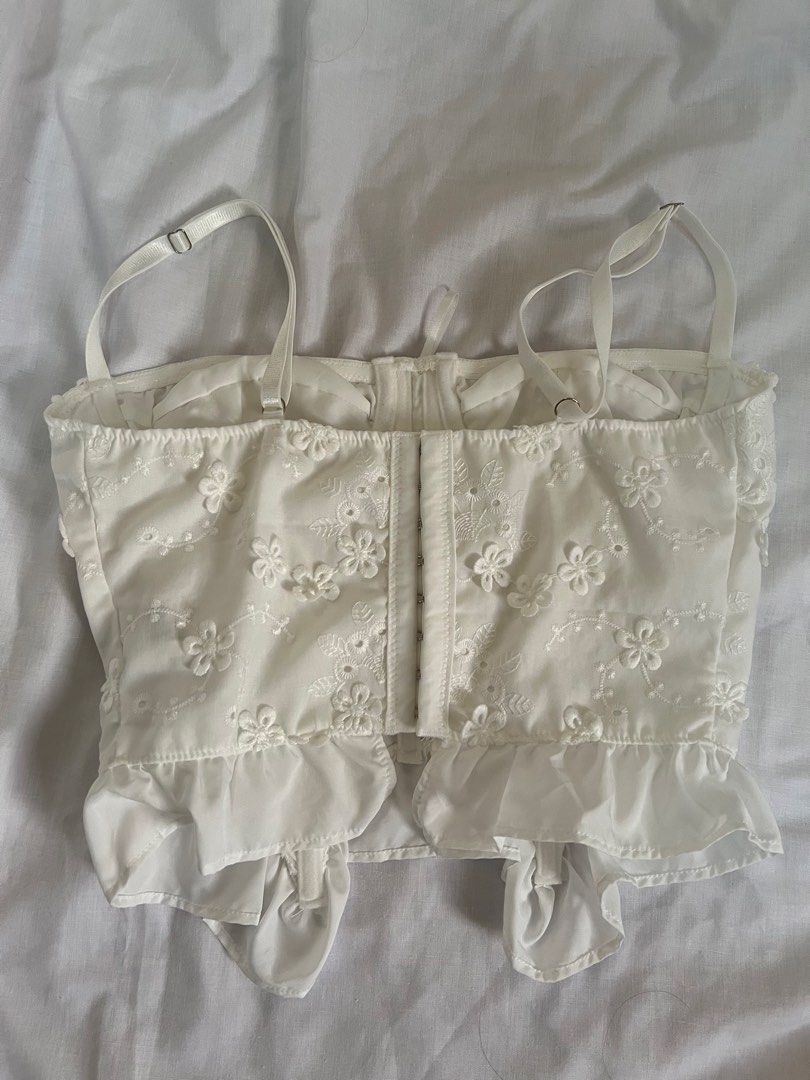 SHEIN White Cami Corset Top (Category: Sleeveless) located in Manila. Submitted by little.fullsun (Listing ID 1465450445, Image 2). Description: - Color: White - Size: XS - Material: 100% polyester - Design: Allover floral embroidery with eyelet details - Features: Adjustable spaghetti straps, structured bust cups, front lace-up tie, and back hook-and-eye closure - Hem: Ruffle hem hitting at the waist - USED ONLY ONCE .