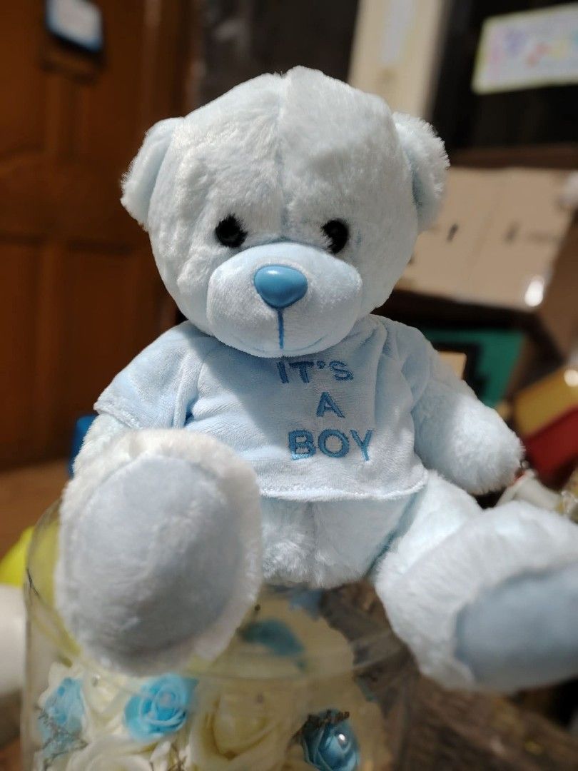 Small Blue It's A Boy Teddy Bear Plush Toy (Category: Plushies & Soft Toys) located in Manila. Submitted by justybelieve2026 (Listing ID 1465496687, Image 1). Description: Light blue teddy bear wearing a matching shirt. Embroidered lettering reads It's A Boy on the front. Soft plush material, plastic blue nose and dark button eyes. Sits upright nicely. Clean and fluffy condition. 11 inches.