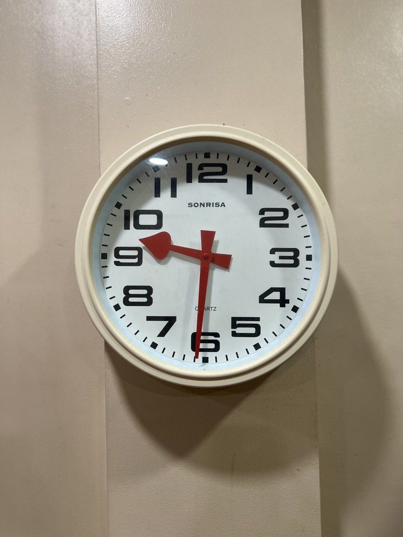 Sonrisa quartz wall clock white dial bold numbers (Category: Clocks) located in Makati City. Submitted by chloescorner (Listing ID 1465393901, Image 1). Description: - Brand: Sonrisa - Type: Quartz wall clock - Design: Clean white face, bold black numbers, tick marks, and striking red hands with a white outer frame - Power: Battery-operated (easy to use without messy cords) - Installation: Easy wall mounting - Style: Minimalist and versatile - Id