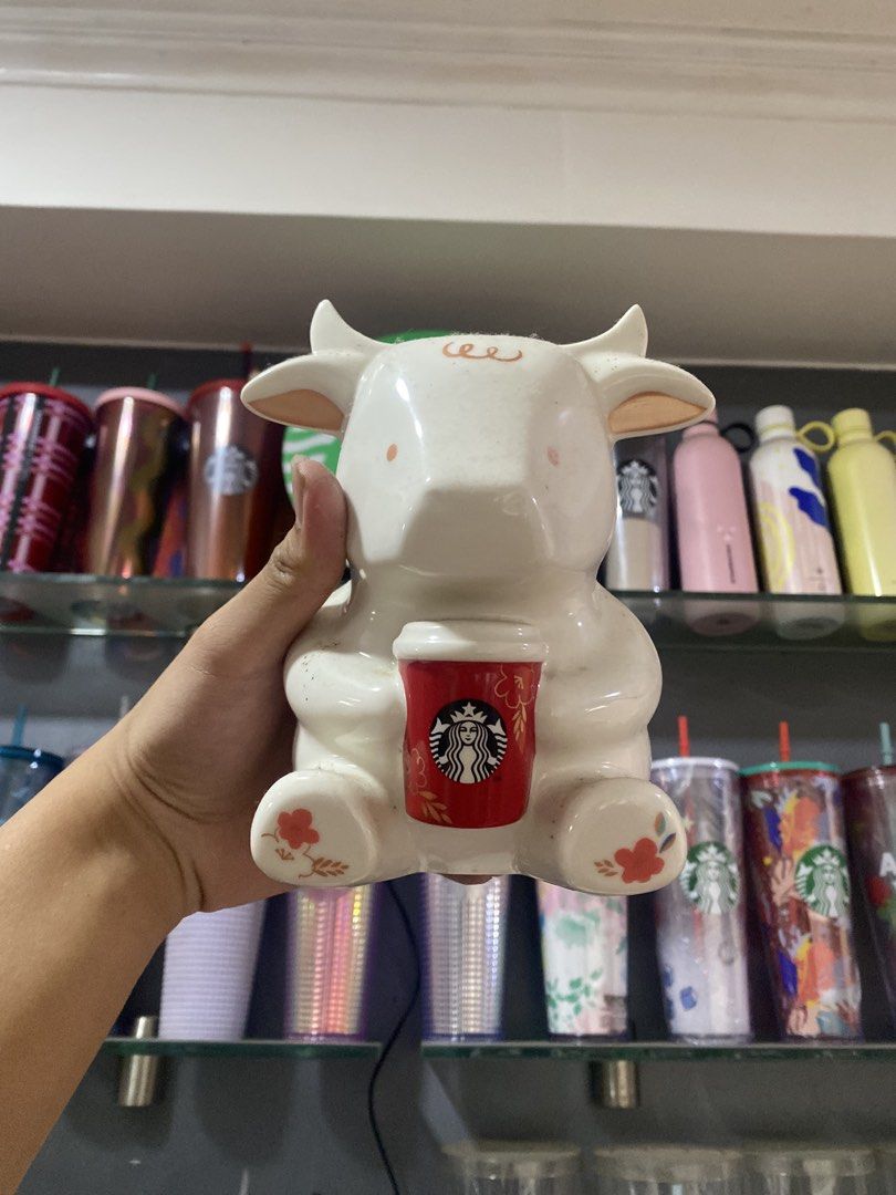 Starbucks Cow Mug with Coffee Cup (Category: Coffee & Tea Tableware) located in Paranaque City. Submitted by jayisnottyfound (Listing ID 1463405845, Image 1). Description: - Adorable Starbucks mug shaped like a cow. - Features a mini Starbucks coffee cup. - Delicate floral details on its feet. - Ideal for Starbucks collectors and cow enthusiasts. - Makes a charming desk or shelf decoration..