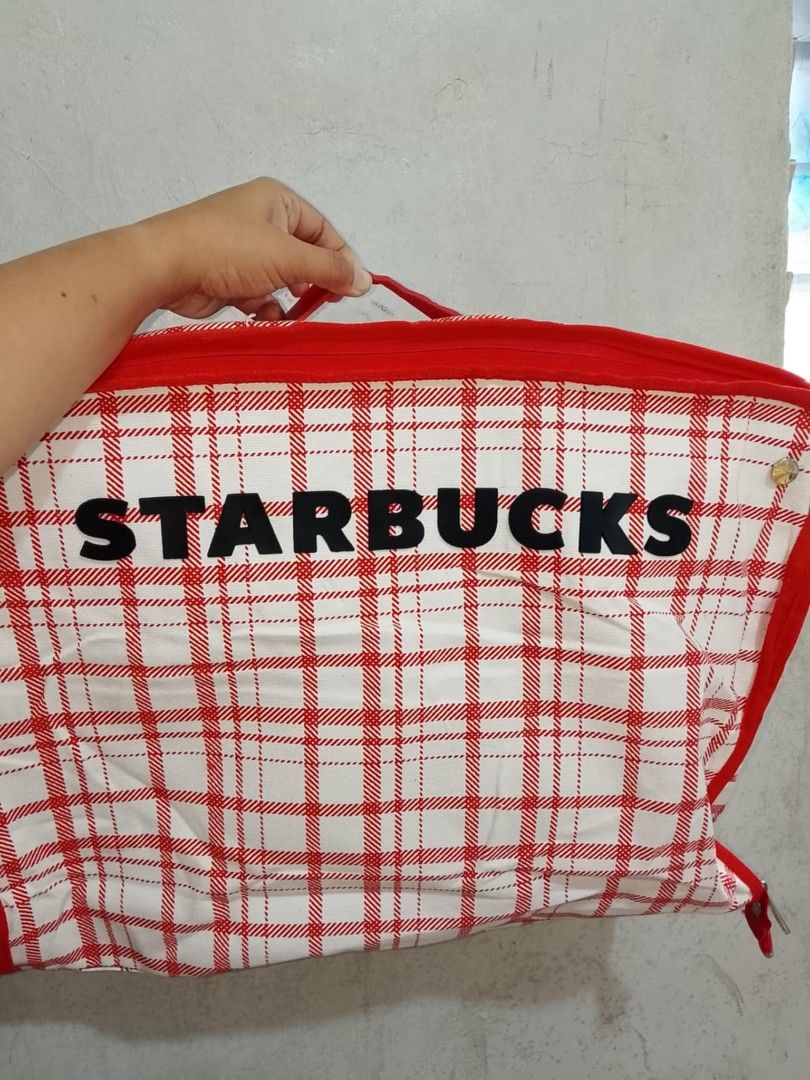 Starbucks Red Plaid Summer Carrier Bag (Category: Tote Bags) located in Santo Tomas. Submitted by noviemolde07815 (Listing ID 1465403989, Image 1). Description: - Authentic Starbucks summer collection carrier bag - Trendy red and white plaid pattern with bold black STARBUCKS lettering - Includes a detachable/attached metal Siren logo pin on the side - Vibrant bright orange interior lining complete with convenient pockets and official tag - Secure