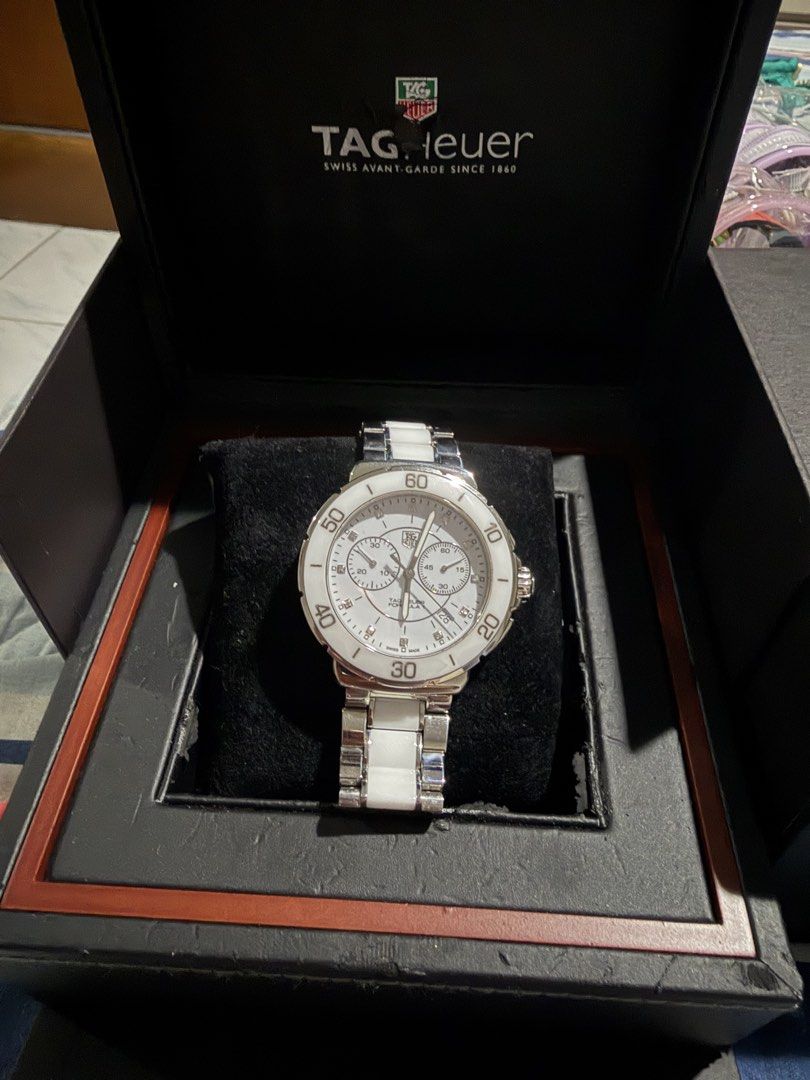Tag Huer Formula 1 Chrono (Category: Luxury Watches) located in Taguig. Submitted by Zyannah (Listing ID 1465466130, Image 1). Description: Preloved but well loved Tag Huer Formula 1 Chrono watch. White face with diamond and white ceramic strap. 41mm face.17.5cm wrist measurement. Can be a unisex watch. Plus shipping. Check status/condition of the boxes on the last photos. The main box has chipped off due to weather and storage. No rush shipping 