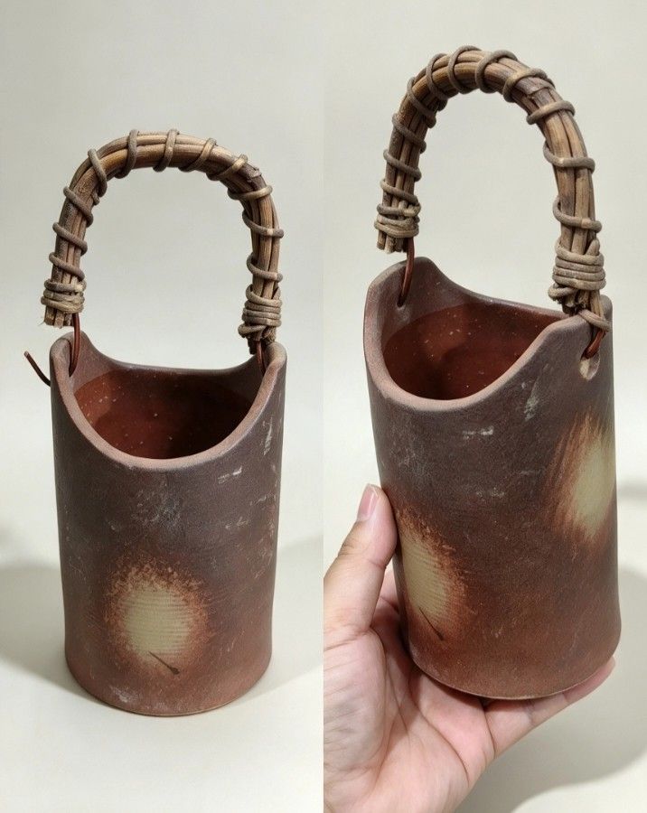 Terracotta Ceramic Vase with Wrapped Handle (Category: Vases & Decorative Bowls) located in Baguio. Submitted by akileshomeprints (Listing ID 1465468344, Image 1). Description: - Hand-crafted brown terracotta ceramic vessel with a rustic look - Unique wrapped twig handle and curved rim design - Textured surface featuring stylish lighter circular gradient patches - Stable flat base for secure display - Ideal for holding dried flowers or as a stand