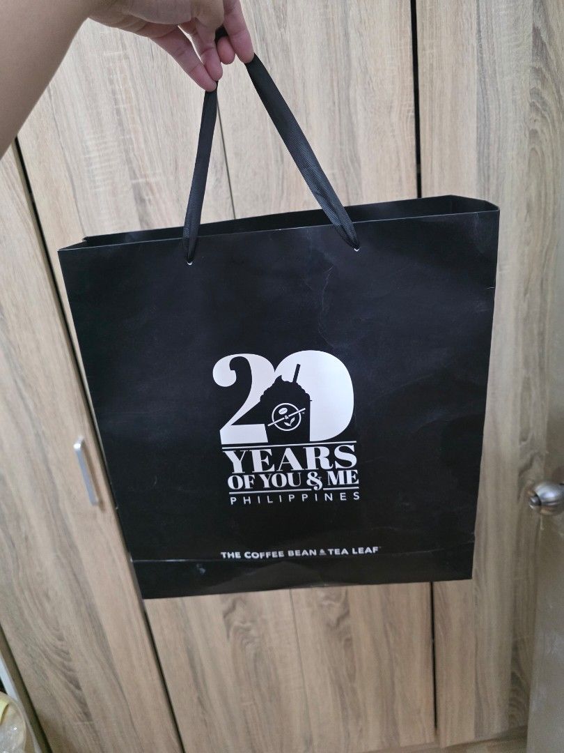 The Coffee Bean and Tea Leaf Canvas Tote Bag (Category: Tote Bags) located in Manila. Submitted by jms_shopping (Listing ID 1465446363, Image 2). Description: - Brand: The Coffee Bean and Tea Leaf - Color: Dark blue canvas with tan faux leather handles and accents - Condition: Brand new with tag still attached to the strap - Closure: Secure top zip closure - Pockets: Convenient front slip pockets with logo patch and interior slip pockets - Extras