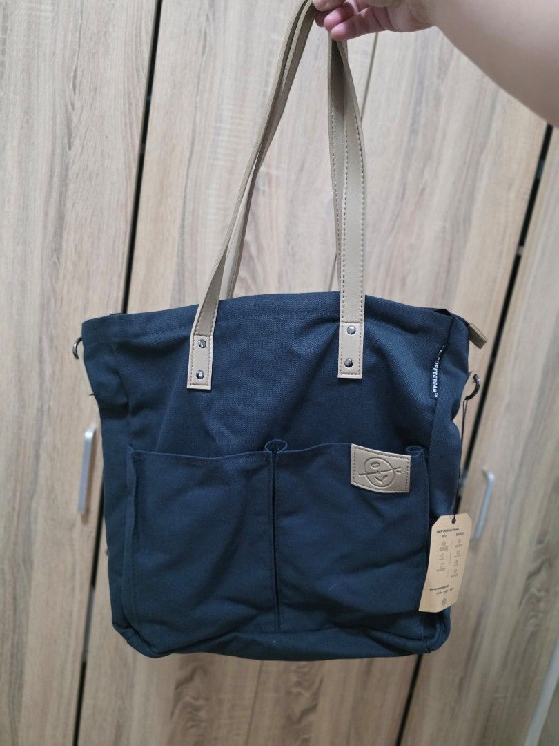 The Coffee Bean and Tea Leaf Canvas Tote Bag (Category: Tote Bags) located in Manila. Submitted by jms_shopping (Listing ID 1465446363, Image 3). Description: - Brand: The Coffee Bean and Tea Leaf - Color: Dark blue canvas with tan faux leather handles and accents - Condition: Brand new with tag still attached to the strap - Closure: Secure top zip closure - Pockets: Convenient front slip pockets with logo patch and interior slip pockets - Extras