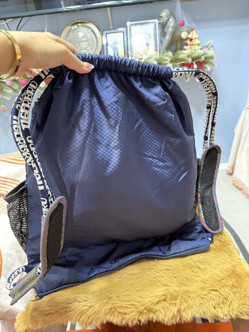 Tigerbro Navy Blue Drawstring Backpack Bag (Category: Backpacks) located in Alaminos. Submitted by jhean1323 (Listing ID 1465449838, Image 2). Description: - Brand: Tigerbro - Color: Navy blue with a large white logo on the front - Material: Honeycomb textured fabric - Compartments: Spacious main interior with inner zip and slip pockets - Pockets: Dual mesh side pockets, front zip pocket, and extra zipped bottom compartment - Straps: Branded shou