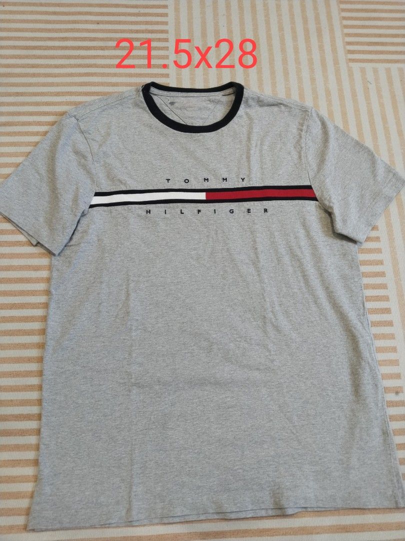 Tommy Hilfiger Grey T-Shirt (Category: Tshirts & Polo Shirts ) located in Manila. Submitted by polding25 (Listing ID 1465386425, Image 1). Description: - Brand: Tommy Hilfiger - Style: Crew neck t-shirt in grey - Details: Contrast black collar trim, red/white/black chest stripe, and front lettering - Material: Soft cotton - Measurements: 21.5 inches chest width x 28 inches length - Condition: Excellent, comes with interior care and country of ori