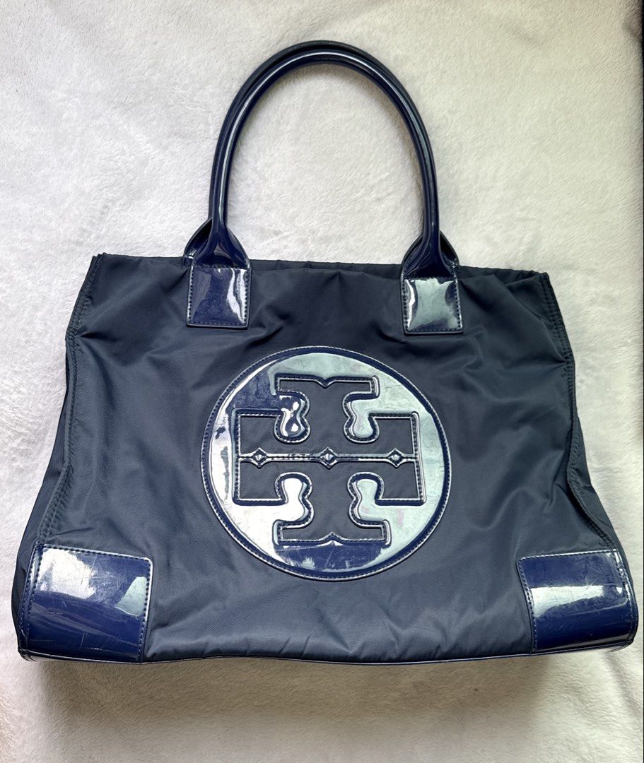 Tory Burch Blue Nylon Tote Bag (Category: Tote Bags) located in Quezon City. Submitted by shane_blueraee (Listing ID 1465401524, Image 1). Description: Authentic Tory Burch Ella Patent Nylon Tote Material: Durable navy blue nylon with glossy patent leather handles, corners, and front logo Interior: Spacious cream canvas lining with zippered pocket Closure: Magnetic snap top closure Condition: few scratches on the glossy patent leather SF c/o buye