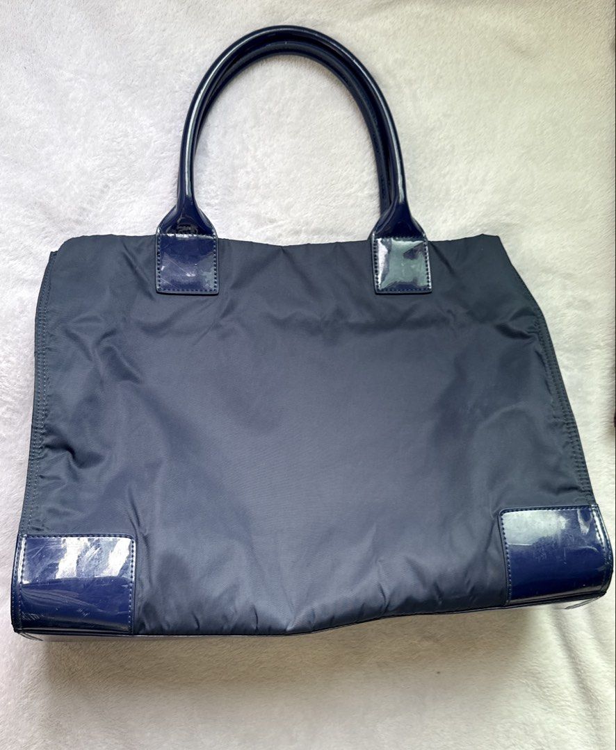 Tory Burch Blue Nylon Tote Bag (Category: Tote Bags) located in Quezon City. Submitted by shane_blueraee (Listing ID 1465401524, Image 2). Description: Authentic Tory Burch Ella Patent Nylon Tote Material: Durable navy blue nylon with glossy patent leather handles, corners, and front logo Interior: Spacious cream canvas lining with zippered pocket Closure: Magnetic snap top closure Condition: few scratches on the glossy patent leather SF c/o buye
