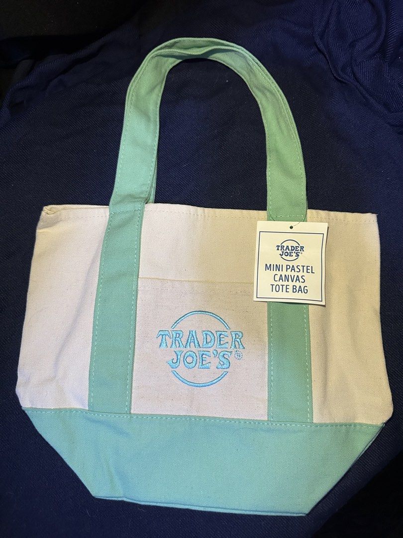 Trader Joe's Mini Pastel Canvas Tote Bag (Category: Tote Bags) located in Mandaluyong City. Submitted by nanokimber71869 (Listing ID 1465560710, Image 2). Description: - Brand new with tag attached - Color: Mint green and white pastel canvas - Material: Durable heavyweight canvas construction - Design: Front pocket featuring a blue embroidered Trader Joe's logo - Features: Double top handles and a structured base for easy storage - Condition: Pri