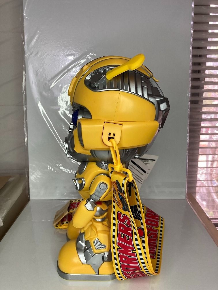 Transformers Bumblebee Popcorn Bucket with Strap (Category: Character Goods) located in Makati City. Submitted by gogokin (Listing ID 1465438204, Image 2). Description: - Official Transformers Bumblebee character popcorn bucket - Made of bright yellow and silver molded plastic - Features working glowing blue light-up eyes - Includes yellow carrying strap with movie imagery and film strip motifs - Brand new with original tag attached - Perfect fun