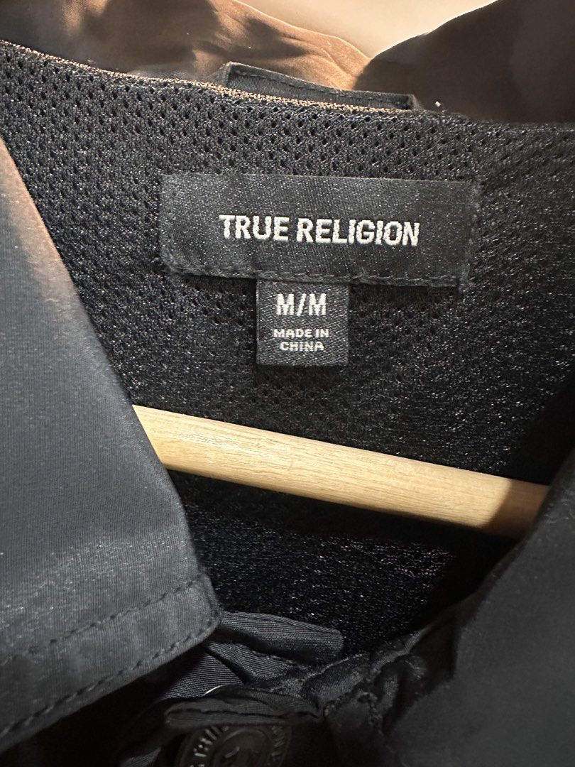 True Religion Basic Coach Jacket (Category: Coats, Jackets and Outerwear) located in Bulacan. Submitted by adoseofluxxee (Listing ID 1465480433, Image 3). Description: - Brand: True Religion - Item: Basic coach jacket - Color: Black - Size: Medium - Material: 100% polyester (shell and lining) - Front: Red True Religion logo text on the chest, button-up closure, side pockets, and collared neckline - Back: Large colourful floral prints with matchin