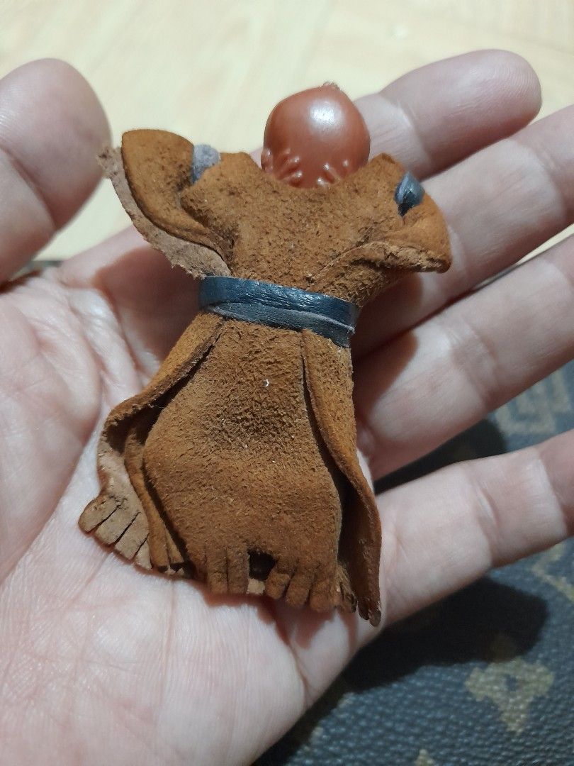 Vintage Mini Celluloid Native American Doll (Category: Vintage Collectibles) located in Bocaue. Submitted by marajapansurplus (Listing ID 1465428054, Image 2). Description: - Miniature swaddled baby doll figurine - Brown suede-like pouch with fringe trim - Detailed sculpted face and dark hair - Secured with black and tan leather straps - Palm-sized collectible item showcasing traditional craftsmanship.