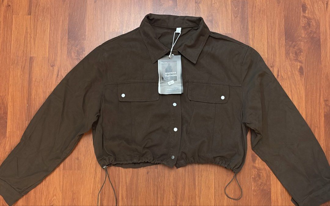 Wanwan Clothing Brown Crop Jacket with Drawstring (Category: Coats, Jackets and Outerwear) located in Silang. Submitted by collectionbyrk (Listing ID 1465517736, Image 3). Description: - Brand: Wanwan Clothing - Color: Deep chocolate brown - Style: Casual streetwear crop jacket - Features: Long sleeves, pointed collar, front button closure, and dual chest flap pockets - Fit: Adjustable drawstring hem on both sides - Condition: Brand new with orig