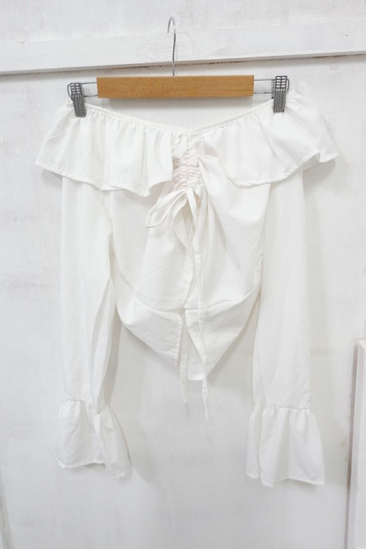 White Off Shoulder Long Sleeve Ruffle Blouse Top (Category: Blouses) located in Quezon City. Submitted by theusualneed (Listing ID 1465444094, Image 1). Description: - Color: Clean white - Style: Off-shoulder with long bell sleeves - Details: Ruffle neckline trim and adjustable tie at the hemline - Fabric: Lightweight and comfortable - Versatility: Easy to pair with your favorite jeans or skirts, ideal for casual days or dates.