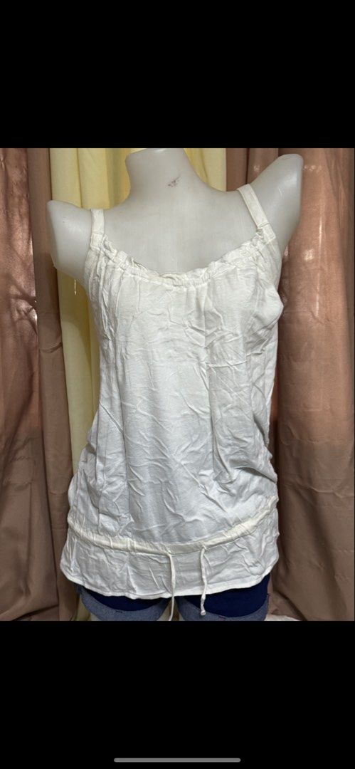 White Tank Top with Ruffle Neckline and Drawstring Hem (Category: Sleeveless) located in Marikina City. Submitted by lorradel (Listing ID 1465393517, Image 3). Description: - Color: White - fits M- L - Material: Lightweight cotton fabric - Design: Ruffled neckline with thick straps - Feature: Adjustable drawstring detail near the bottom hem - Style: Simple and casual, ideal for hot weather or layering under cardigans - might have washable stain d