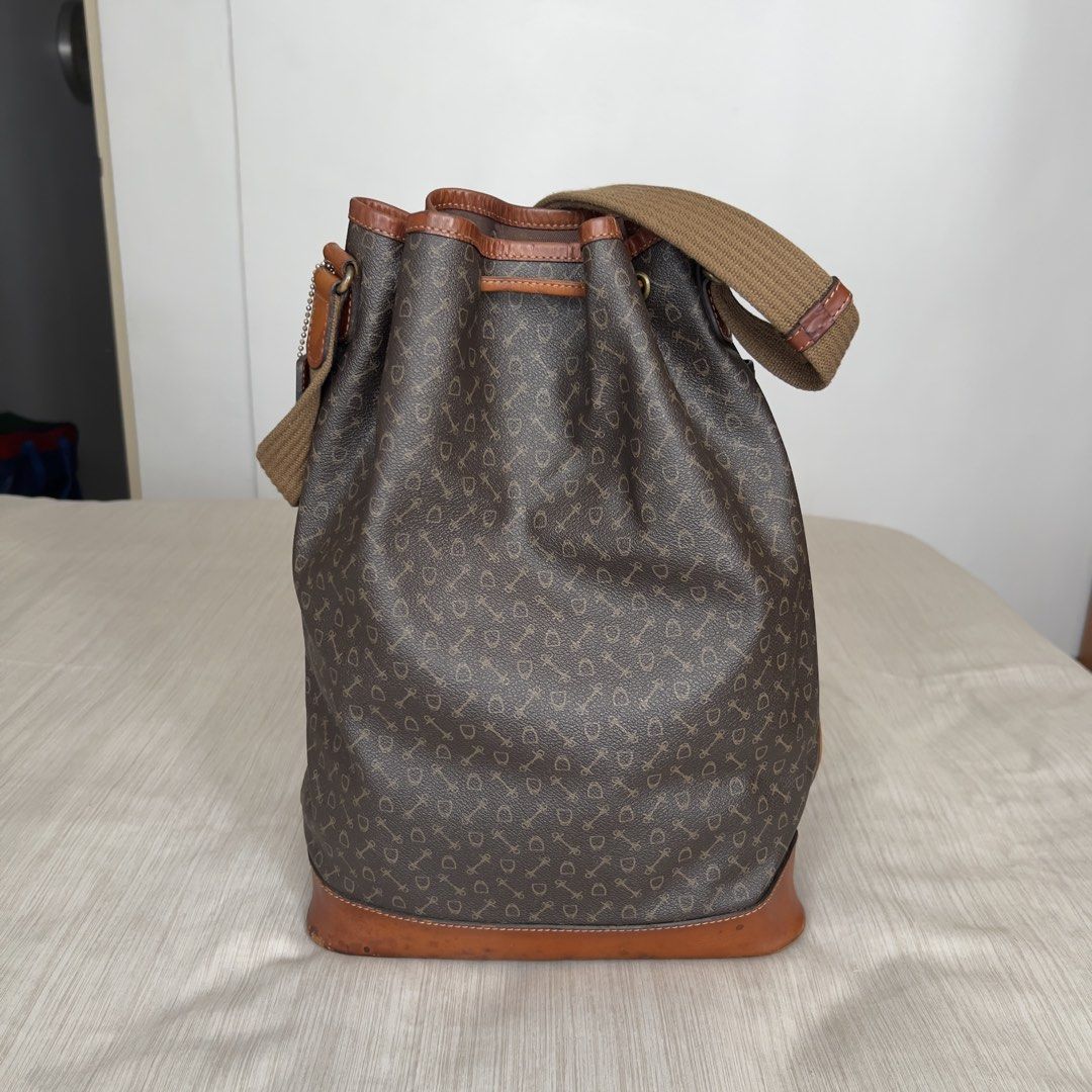WHY Brown Monogram Leather Bucket Bag with Canvas Strap (Category: Shoulder Bags) located in Pasig City. Submitted by jenscloset86 (Listing ID 1465425525, Image 3). Description: Brand: WHY Japanese heritage brand Why (Why Co., Ltd., established in 1966) known for its equestrian-inspired harness and bridle motifs. • Brown monogram bucket bag with all-over key and shield pattern • Drawstring closure with a vertical front zipper for easy access • Ge