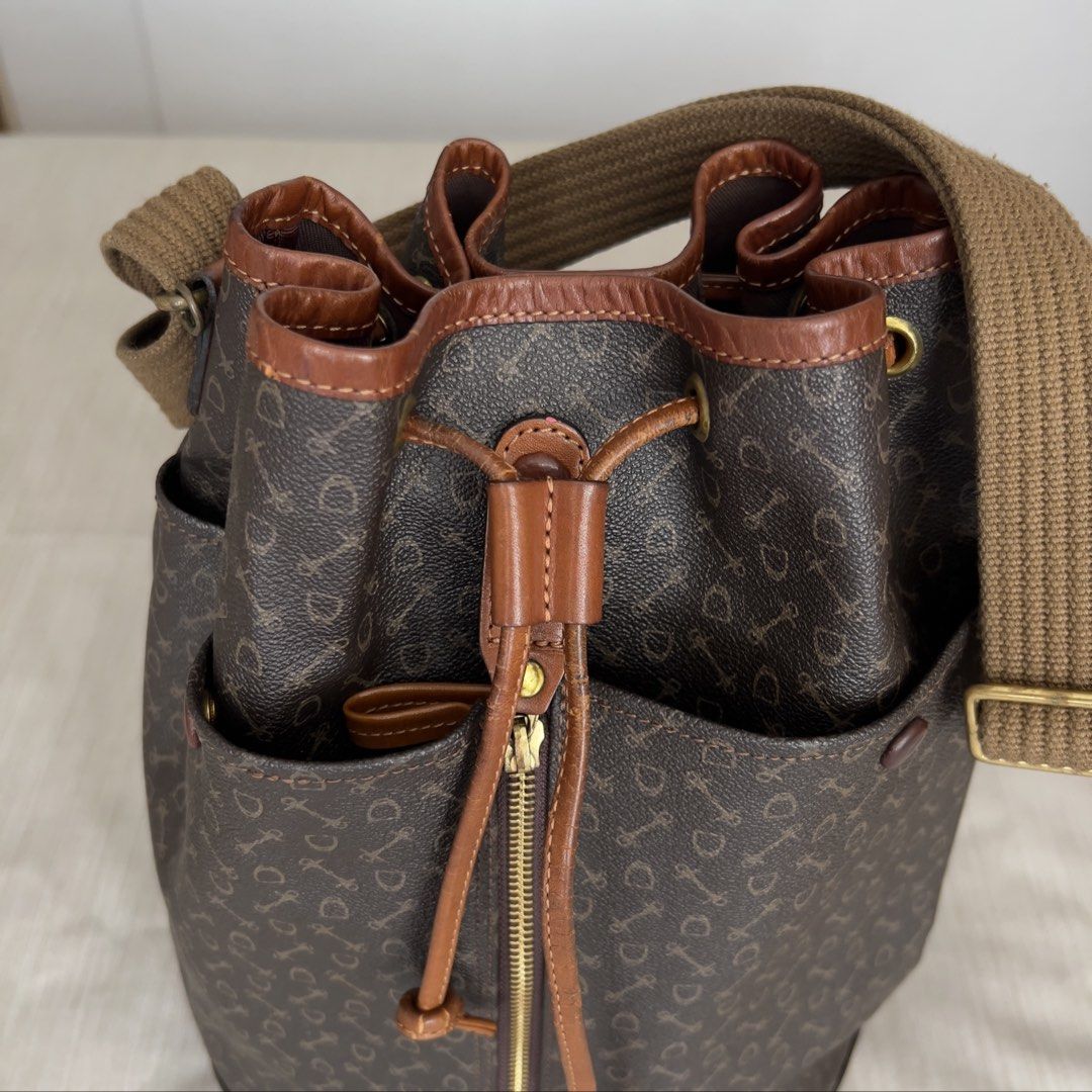 WHY Brown Monogram Leather Bucket Bag with Canvas Strap (Category: Shoulder Bags) located in Pasig City. Submitted by jenscloset86 (Listing ID 1465425525, Image 2). Description: Brand: WHY Japanese heritage brand Why (Why Co., Ltd., established in 1966) known for its equestrian-inspired harness and bridle motifs. • Brown monogram bucket bag with all-over key and shield pattern • Drawstring closure with a vertical front zipper for easy access • Ge