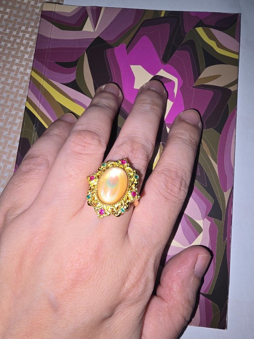 Yellow MOP statement ring (Category: Rings) located in Santa Rosa. Submitted by crystal1.0 (Listing ID 1465482106, Image 2). Description: - Design: Vintage-inspired gold-tone statement ring with intricate filigree detailing - Center Stone: Stunning oval iridescent opal - Accents: Small pinkish-red and green gemstones bordering the center - Fit: Comfortable for everyday or special occasion wear - Style: A vibrant piece that instantly adds color an