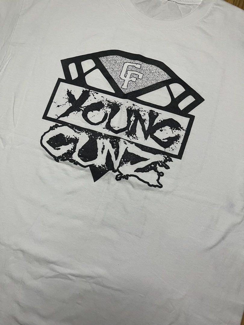 Young Gunz Graphic Tee White 23x31 (Category: Tshirts & Polo Shirts ) located in Cebu City. Submitted by guttathreads (Listing ID 1465429806, Image 2). Description: - Style: Casual streetwear white t-shirt - Design: 'Young Gunz' and 'CF' diamond graphic on front - Back: Large textured dot-pattern 'CF' logo - Fit: Short sleeves with a classic crew neck - Condition: Brand new / Excellent quality.
